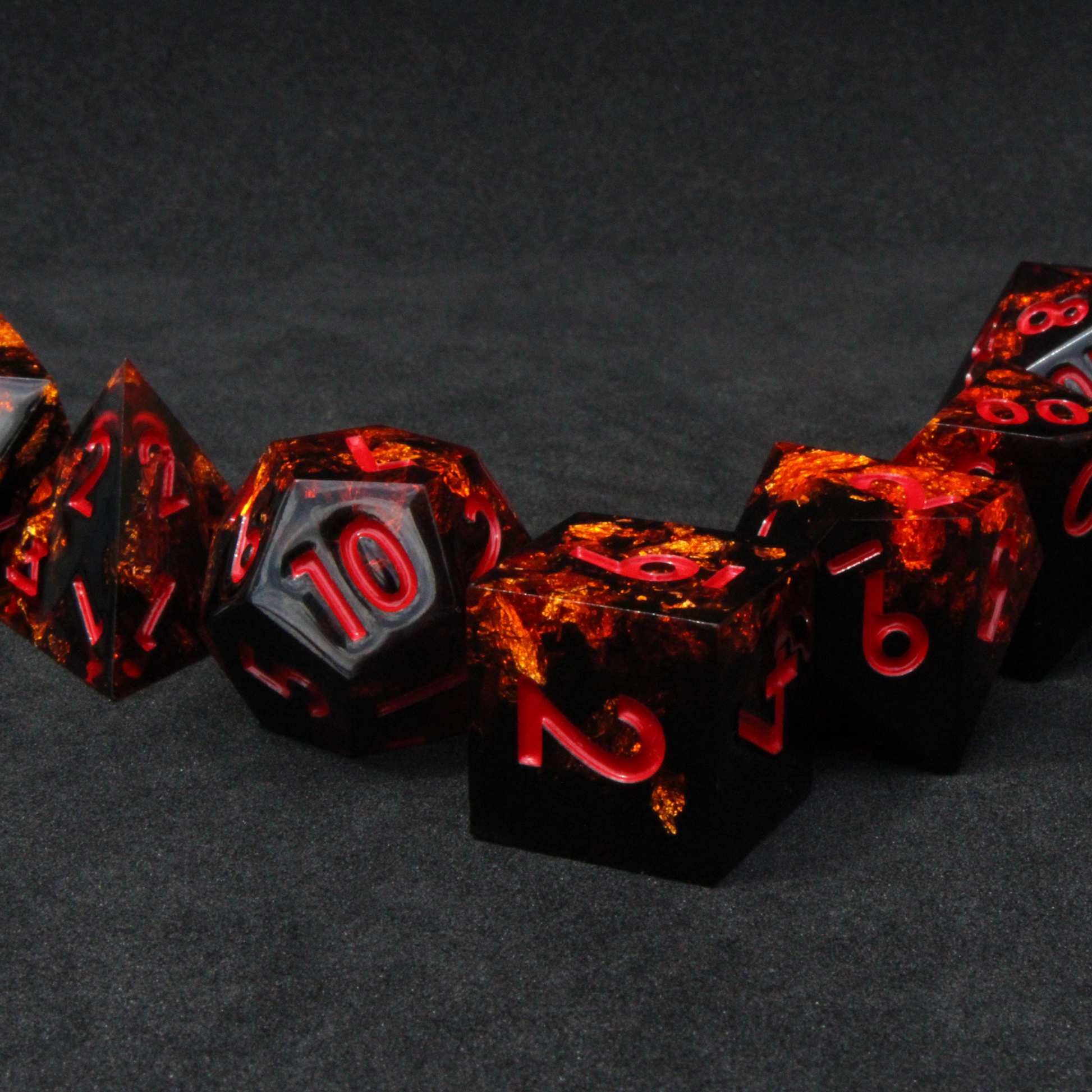 Black and orange sharp edge dnd dice set made of resin and made to look like fire. These polyhedral dice are used to play TTRPGs like Dungeons & Dragons / D&D and Pathfinder.