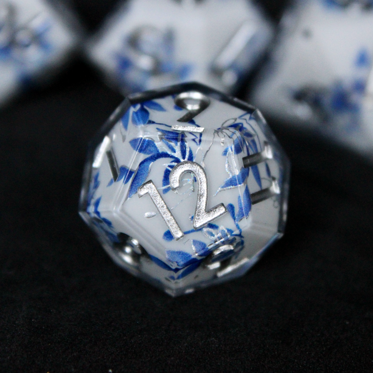 A bright white DND dice set with blue and silver flower patterns on it. The dice are used for TTRPGs like DnD / D&D / Dungeons & Dragons and Pathfinder.