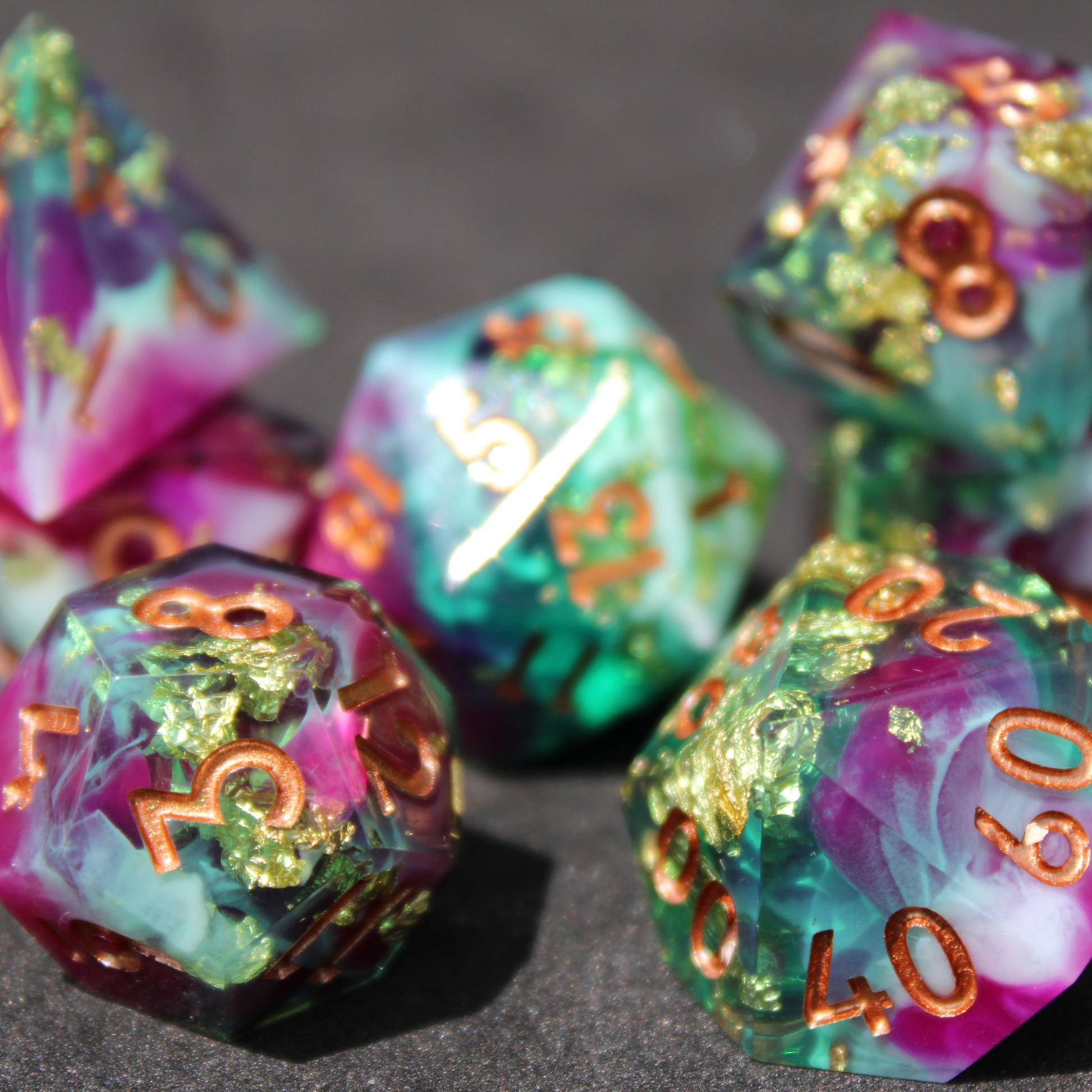 Purple blue and green sharp edge dice made of resin. These polyhedral dice are used for playing TTRPGs like Dungeons & Dragons (D&D / DND) and Pathfinder.