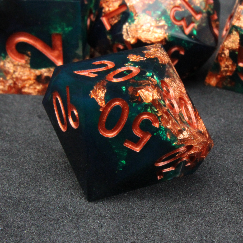 Dark green and black resin sharp edge dice with copper flakes and glitter inside it. The polyhedral dice are used for tabletop roleplaying games like Dungeons & Dragons / DND / D&D and Pathfinder.