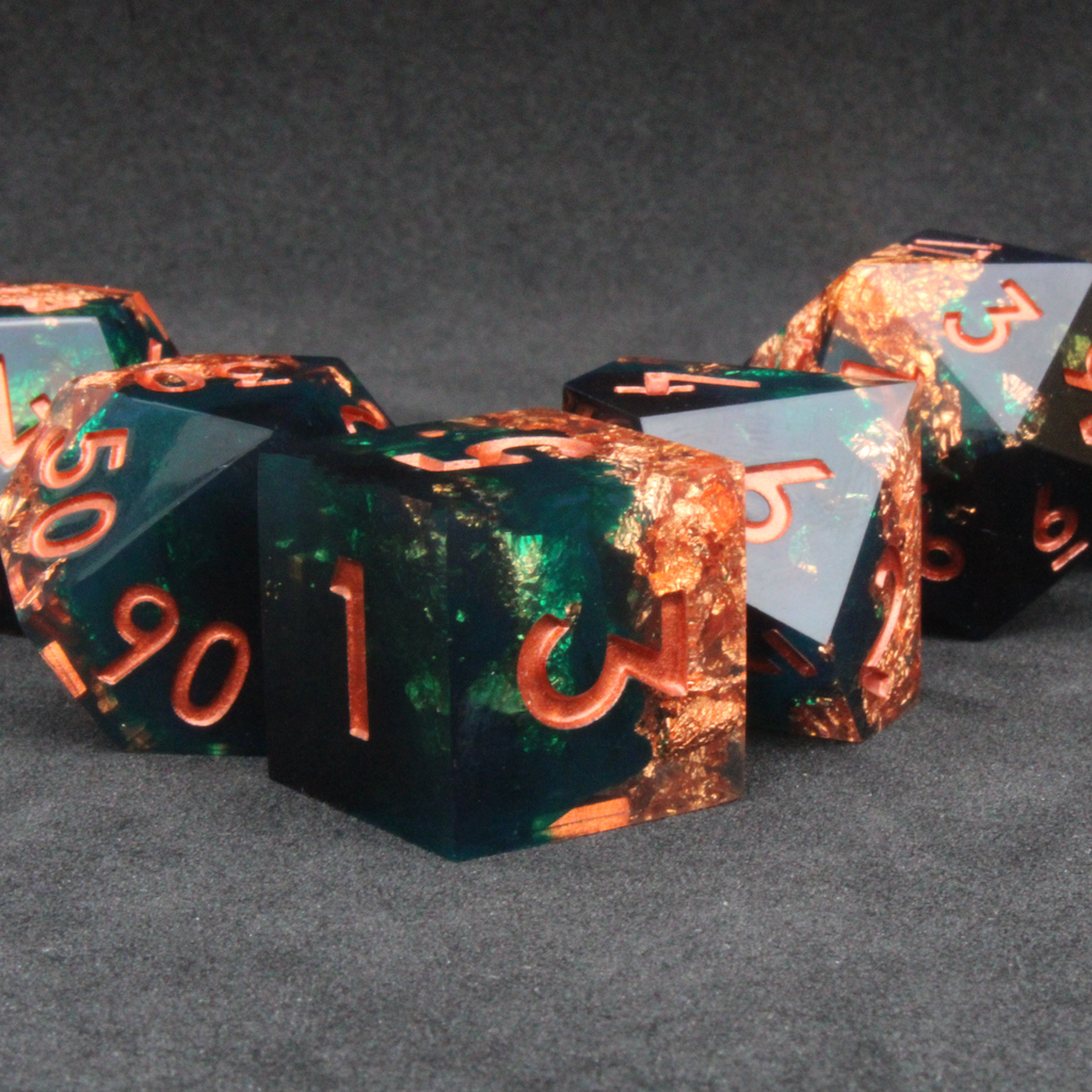 Dark green and black resin sharp edge dice with copper flakes and glitter inside it. The polyhedral dice are used for tabletop roleplaying games like Dungeons & Dragons / DND / D&D and Pathfinder.