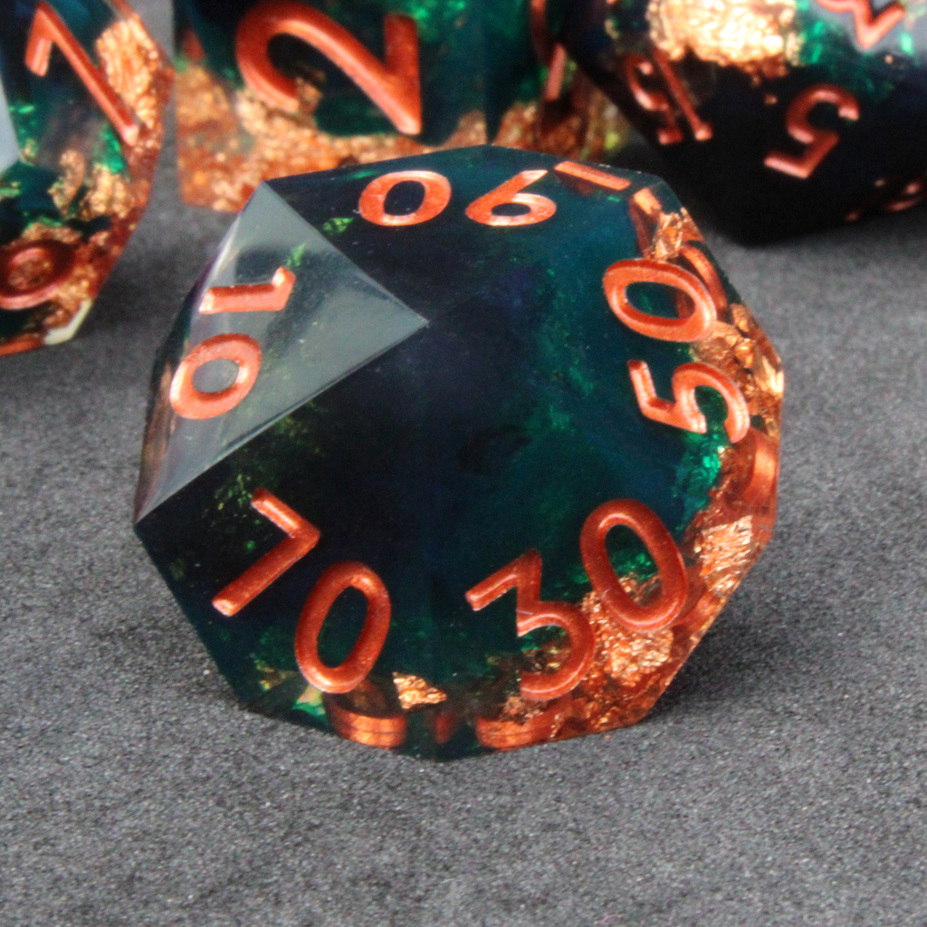 Dark green and black resin sharp edge dice with copper flakes and glitter inside it. The polyhedral dice are used for tabletop roleplaying games like Dungeons & Dragons / DND / D&D and Pathfinder.