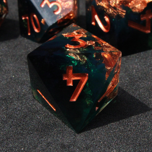 Dark green and black resin sharp edge dice with copper flakes and glitter inside it. The polyhedral dice are used for tabletop roleplaying games like Dungeons & Dragons / DND / D&D and Pathfinder.