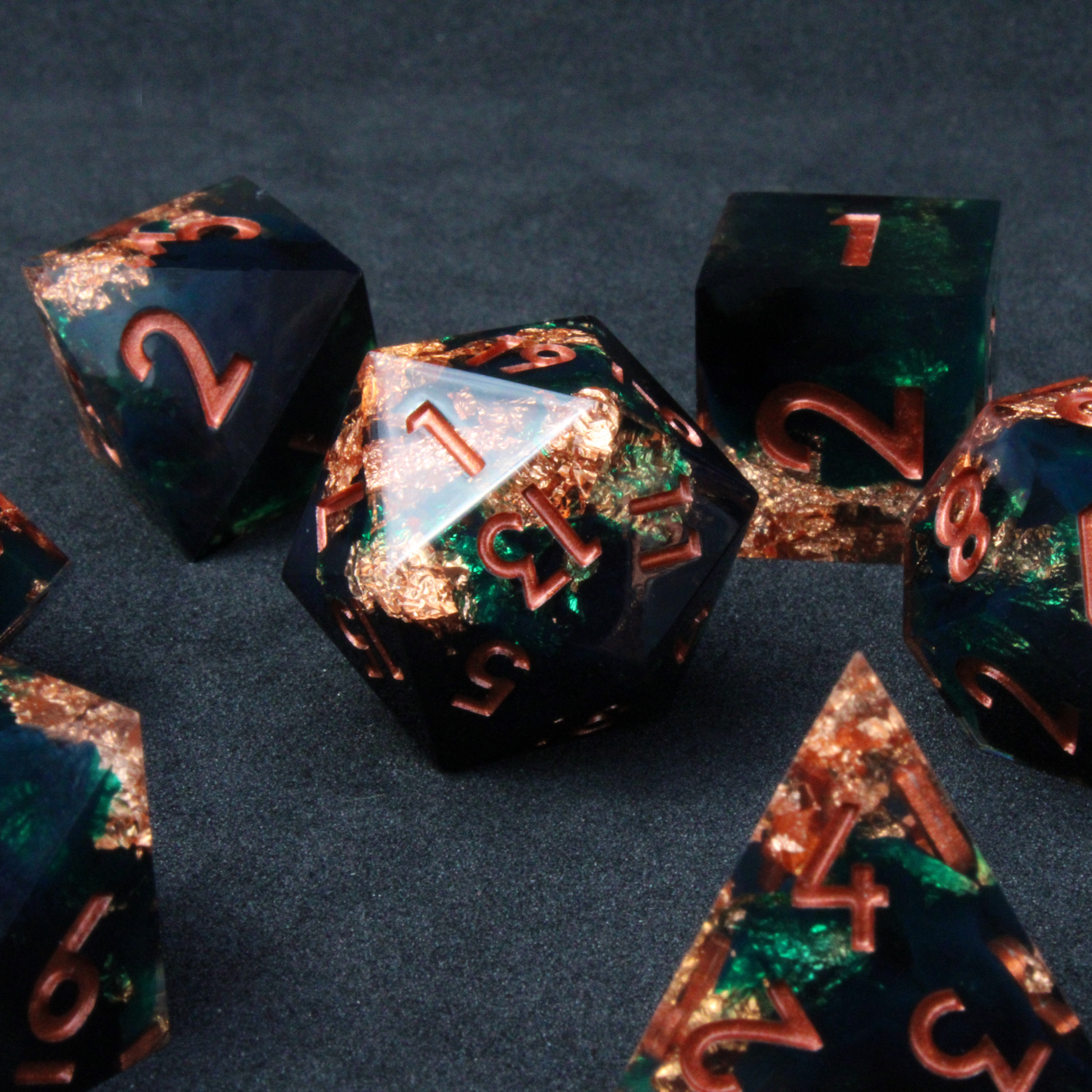 Dark green and black resin sharp edge dice with copper flakes and glitter inside it. The polyhedral dice are used for tabletop roleplaying games like Dungeons & Dragons / DND / D&D and Pathfinder.