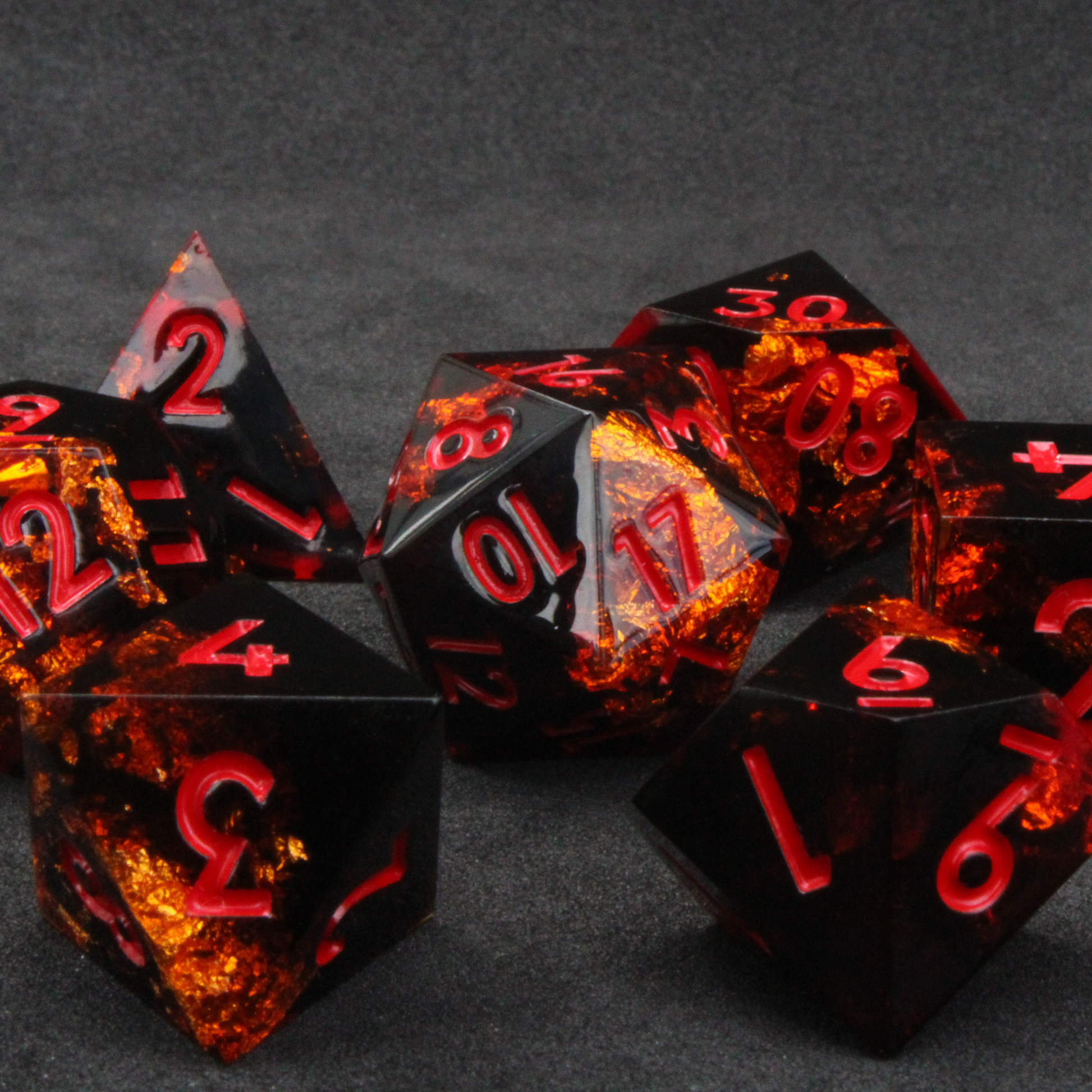 Black and orange sharp edge dnd dice set made of resin and made to look like fire. These polyhedral dice are used to play TTRPGs like Dungeons & Dragons / D&D and Pathfinder. 