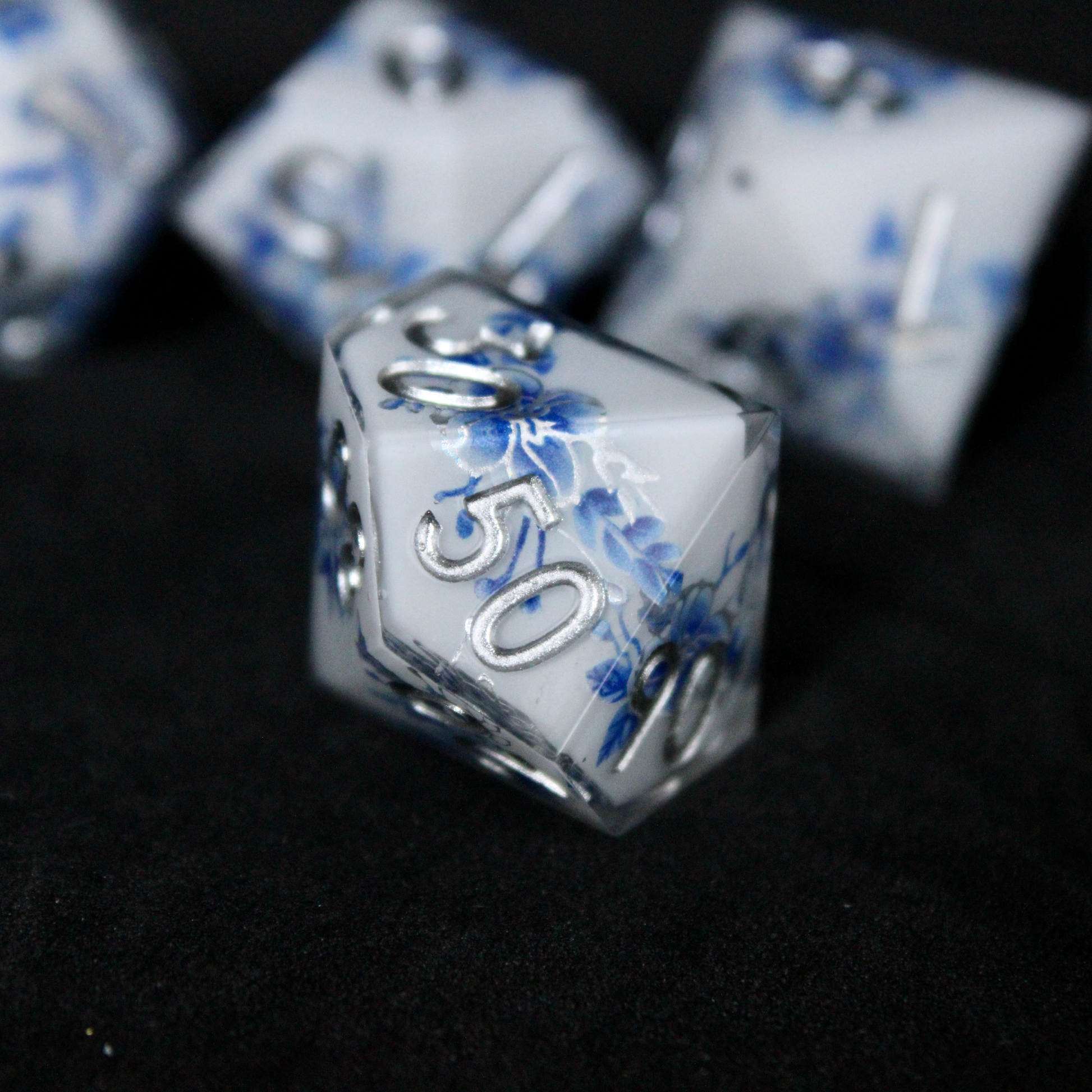 A bright white DND dice set with blue and silver flower patterns on it. The dice are used for TTRPGs like DnD / D&D / Dungeons & Dragons and Pathfinder. 