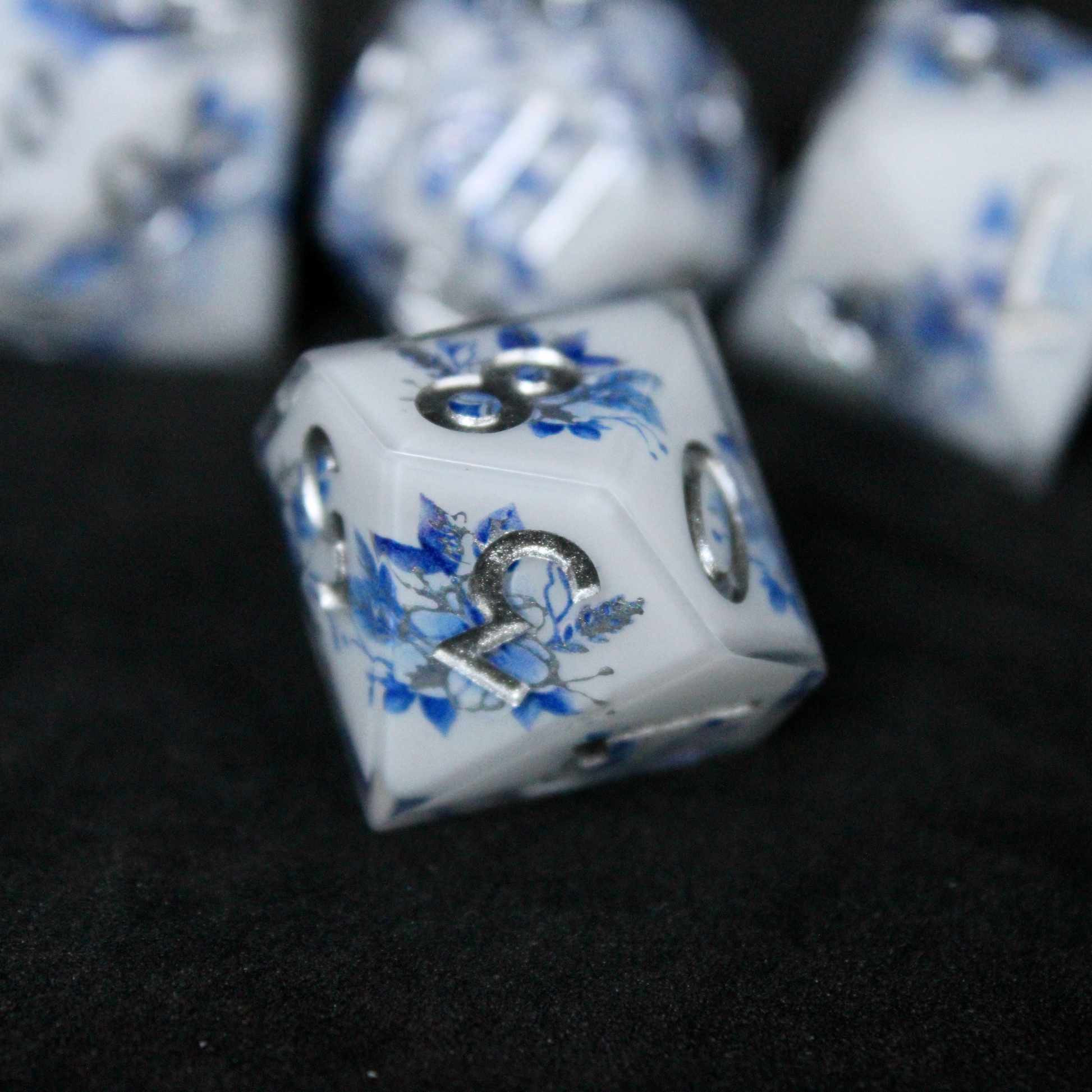 A bright white DND dice set with blue and silver flower patterns on it. The dice are used for TTRPGs like DnD / D&D / Dungeons & Dragons and Pathfinder. 
