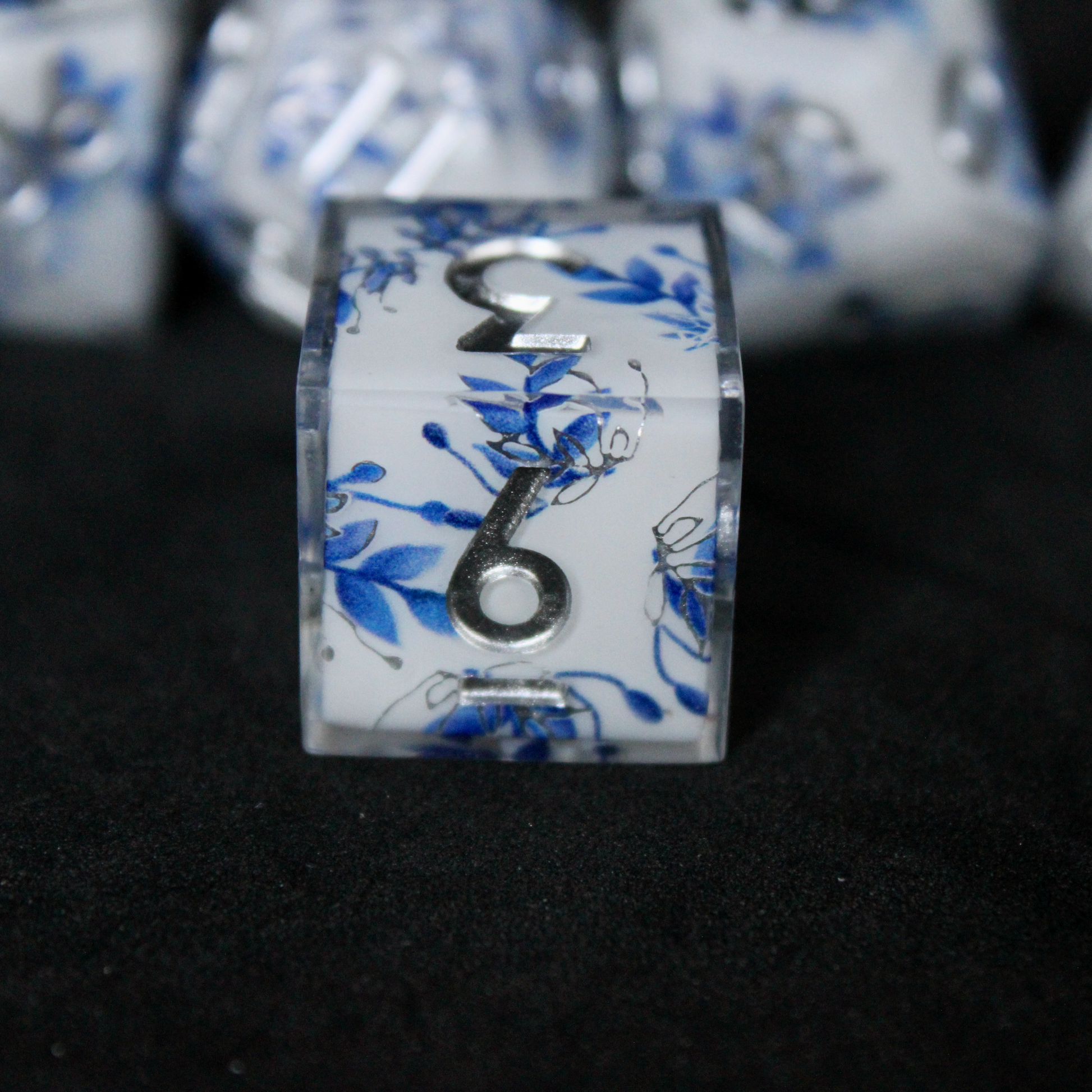 A bright white DND dice set with blue and silver flower patterns on it. The dice are used for TTRPGs like DnD / D&D / Dungeons & Dragons and Pathfinder. 