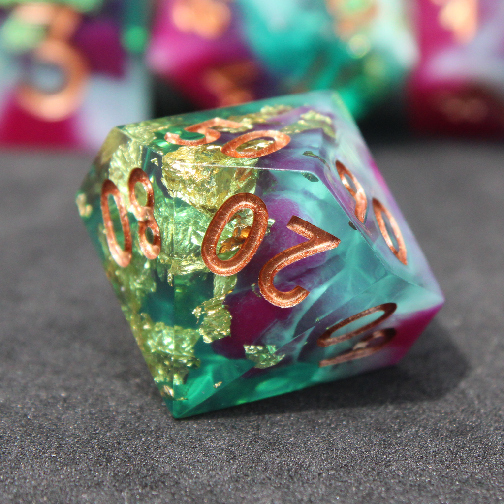 Purple blue and green sharp edge dice made of resin. These polyhedral dice are used for playing TTRPGs like Dungeons & Dragons (D&D / DND) and Pathfinder.