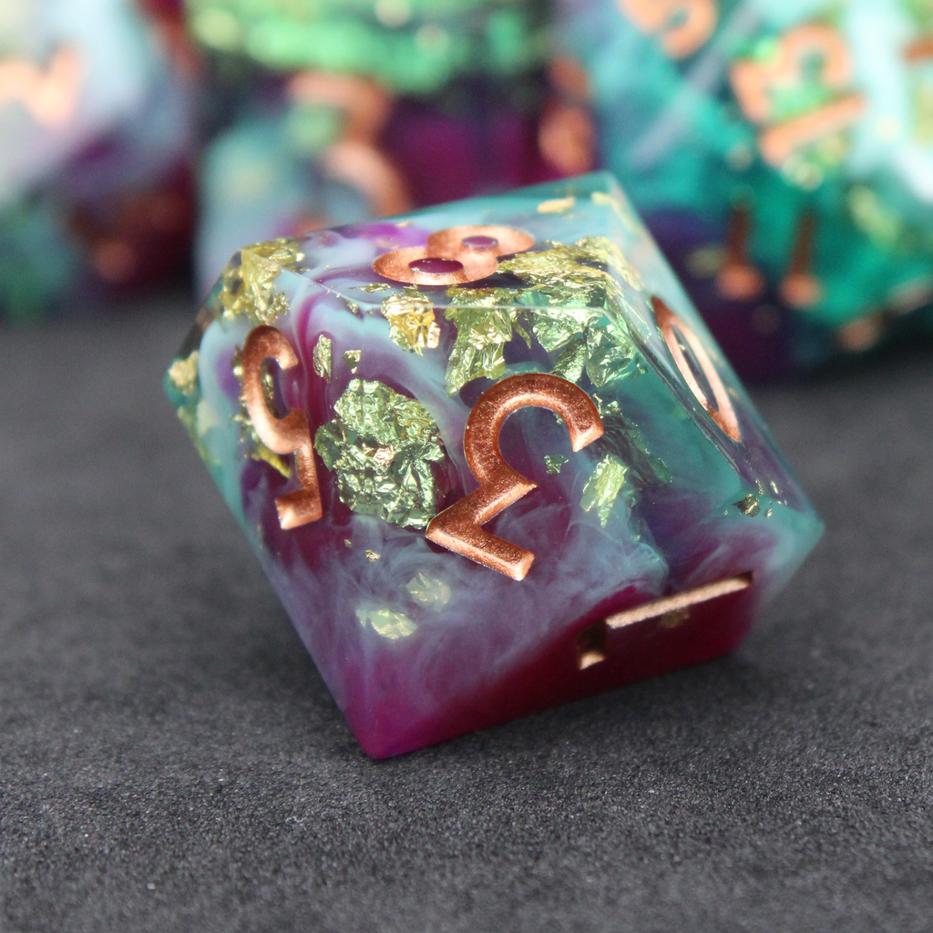 Purple blue and green sharp edge dice made of resin. These polyhedral dice are used for playing TTRPGs like Dungeons & Dragons (D&D / DND) and Pathfinder.