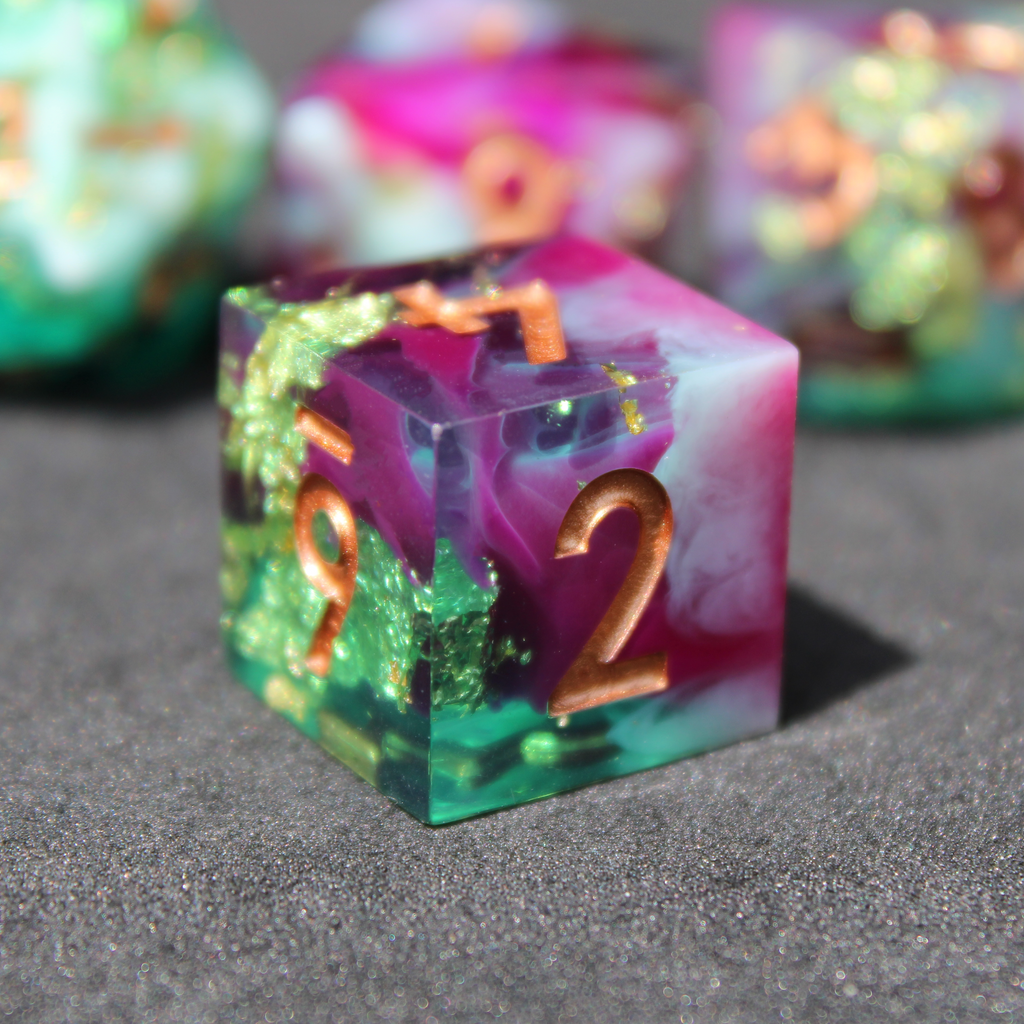 Purple blue and green sharp edge dice made of resin. These polyhedral dice are used for playing TTRPGs like Dungeons & Dragons (D&D / DND) and Pathfinder.