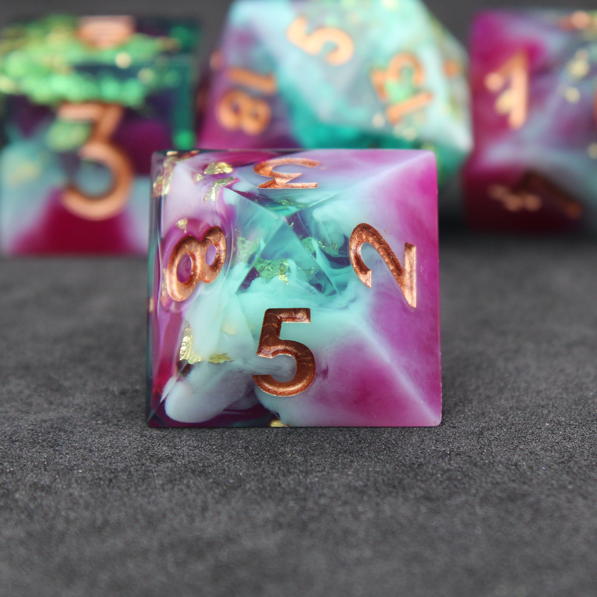 Purple blue and green sharp edge dice made of resin. These polyhedral dice are used for playing TTRPGs like Dungeons & Dragons (D&D / DND) and Pathfinder.