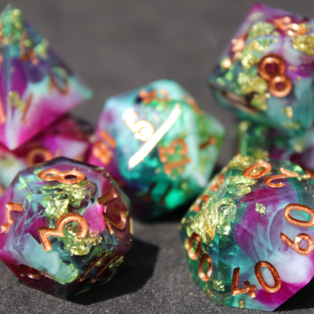 Purple blue and green sharp edge dice made of resin. These polyhedral dice are used for playing TTRPGs like Dungeons & Dragons (D&D / DND) and Pathfinder.